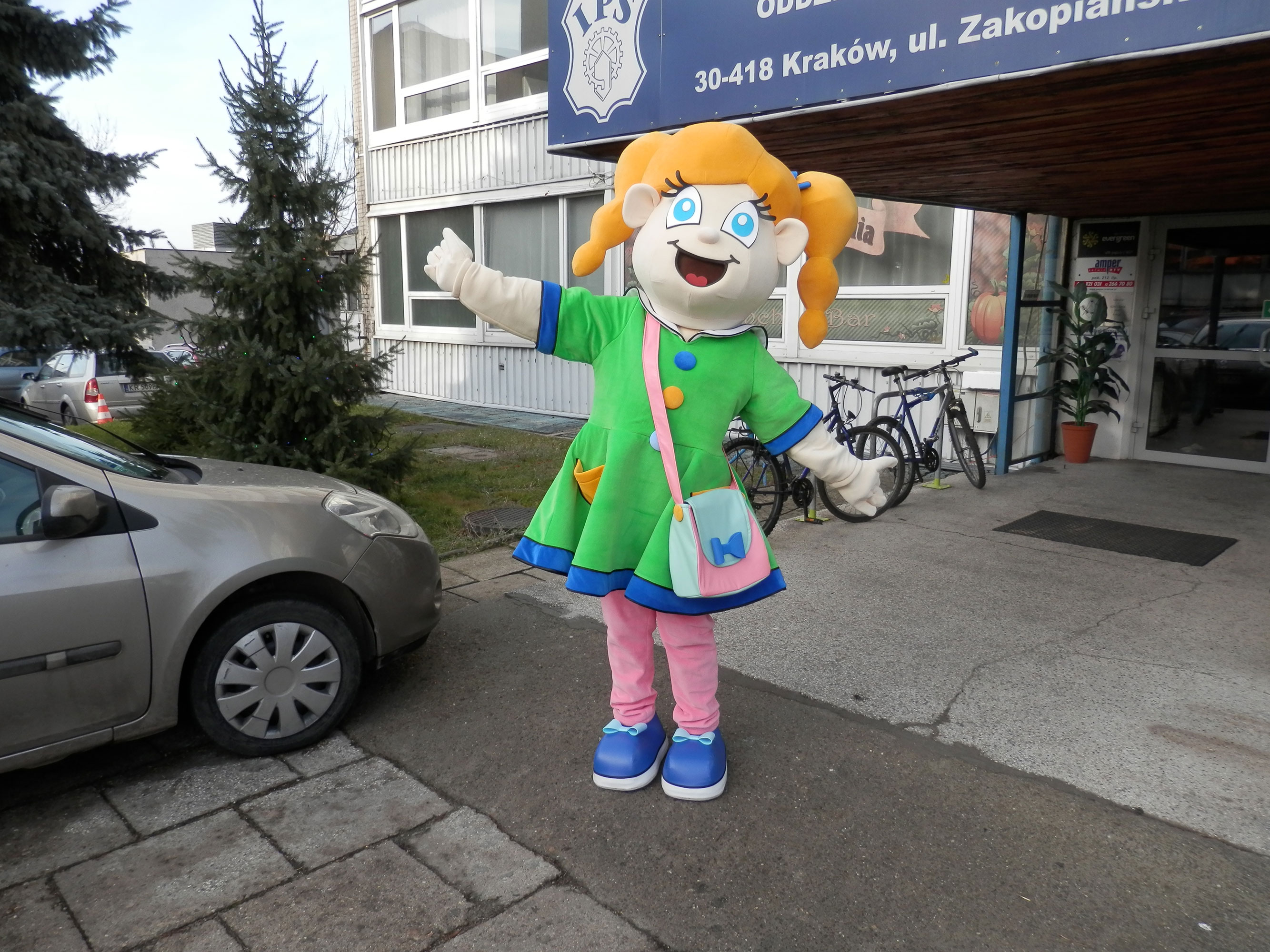 Fotografia przedstawia jak modna blondynka dziewczyna ubrana w strój dziewczyny disco stoi przed drzwiami wejściowymi do budynku  